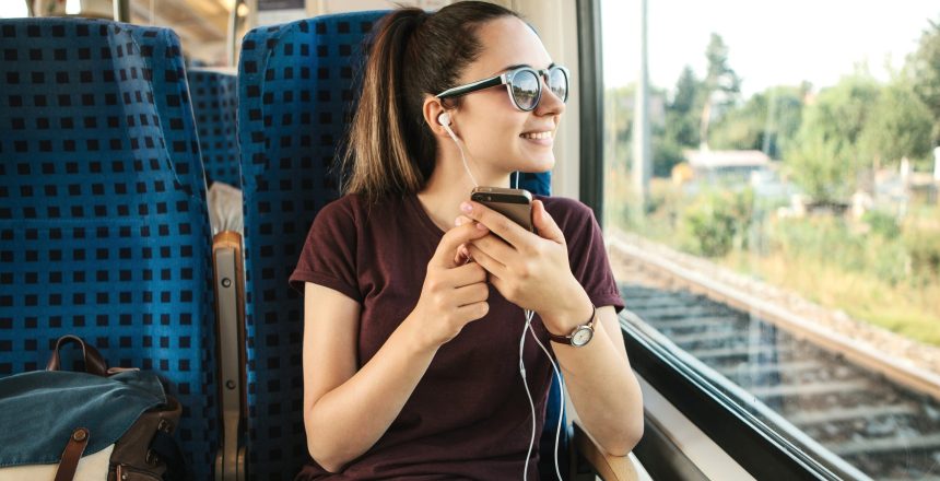 woman listening to streaming audio on her commute, woman streaming audio on the train, premium streaming audio