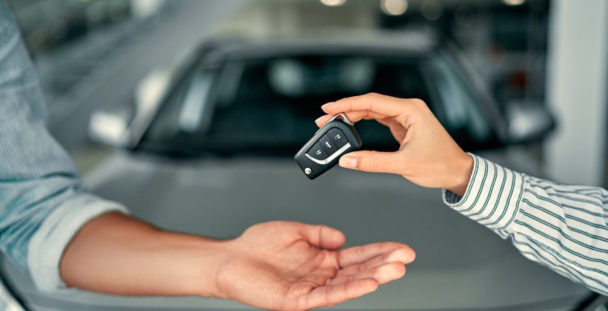 two people exchanging car keys in front of a car