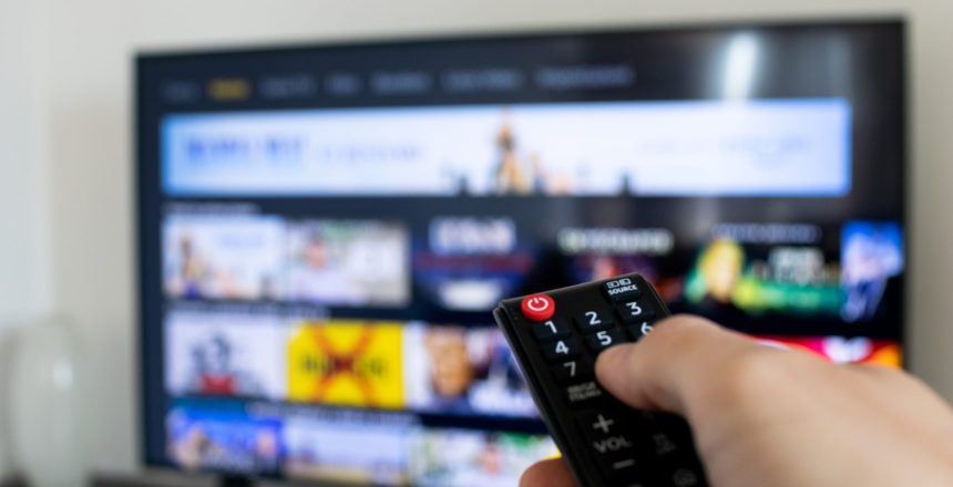 person holding remote up to a TV, streaming services, connected tv