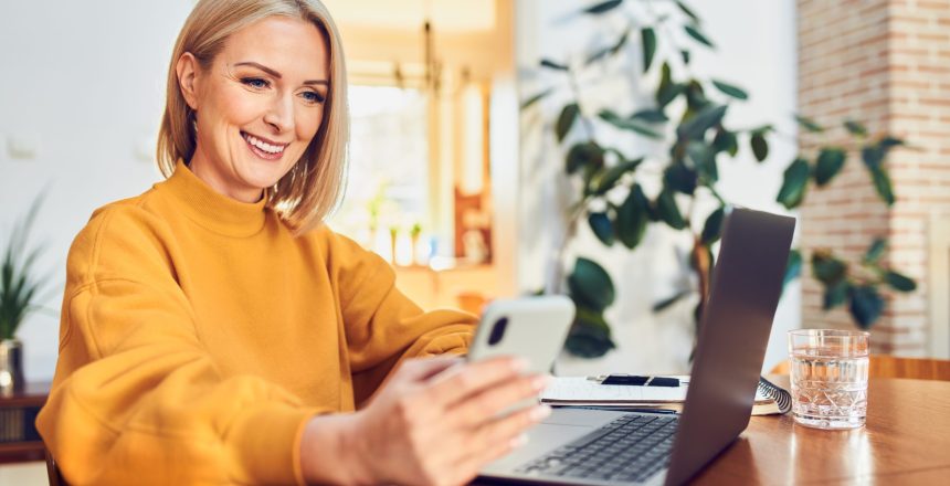 Portrait,Of,Happy,Middle,Aged,Woman,Using,Phone,And,Laptop