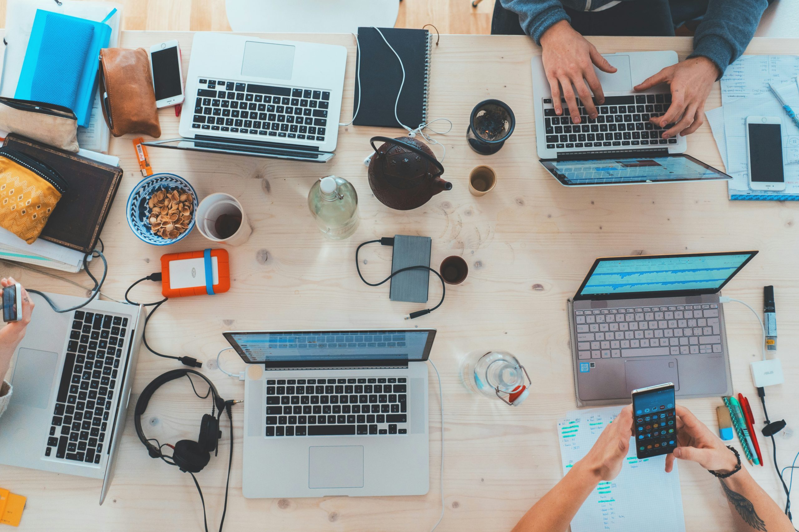 Overhead view of a group sitting around a table on their various digital devices