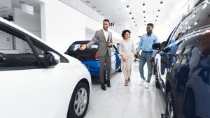 auto in-market, car shoppers, automotive dealership, car salesman speaking to couple browsing for a new car