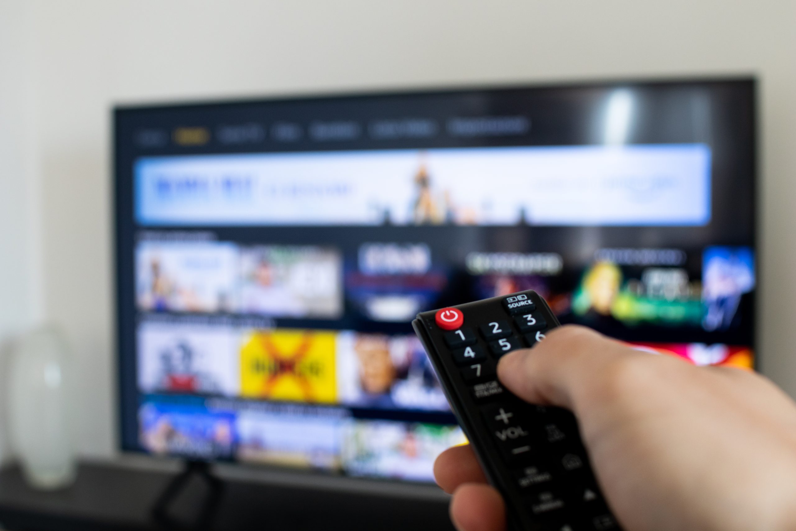 person holding remote up to a TV, streaming services, connected tv